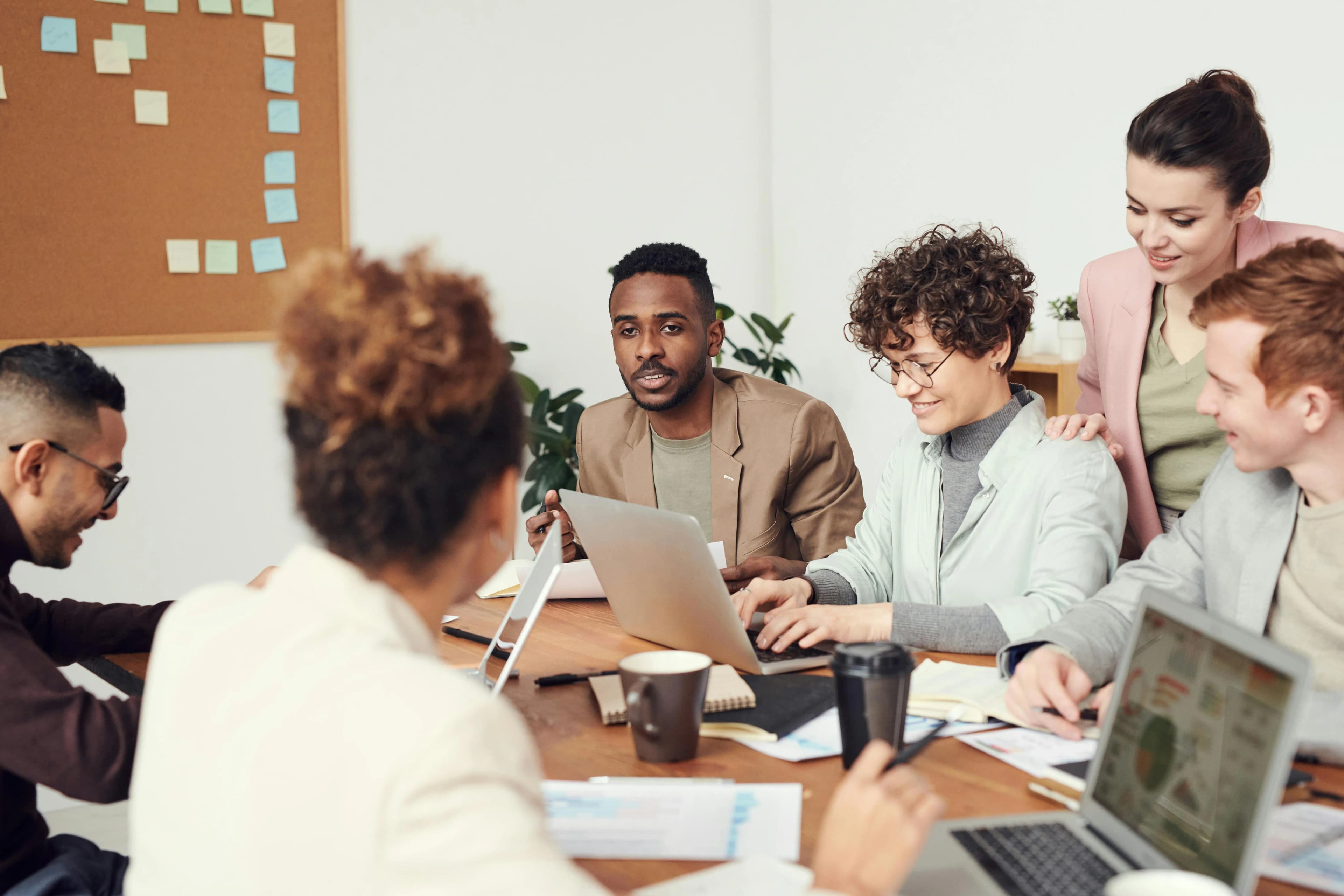 Group of professionals having a collaborative business meeting around a table with laptops and documents.