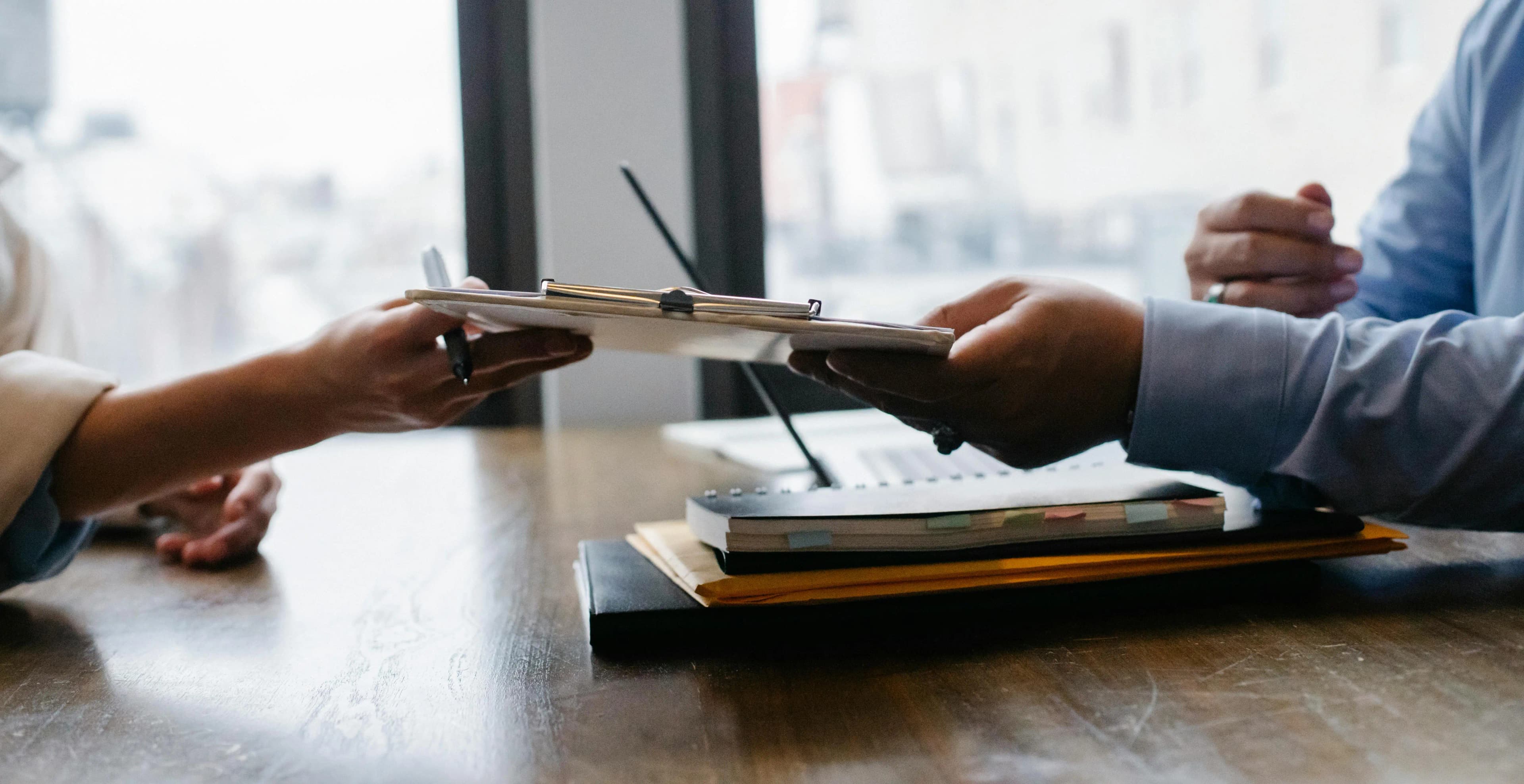 Person handing a clipboard to another professional.