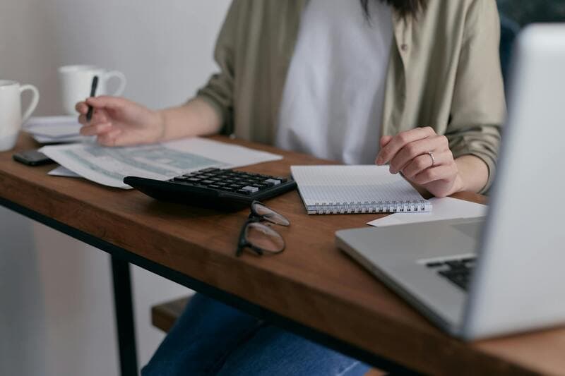 A person looking at documents and using a calculator.