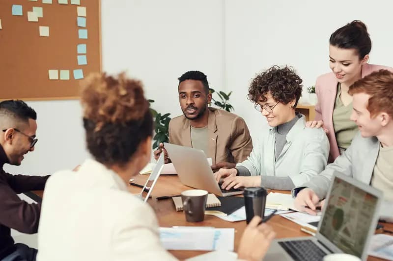 Group of professionals having a collaborative business meeting around a table with laptops and documents.