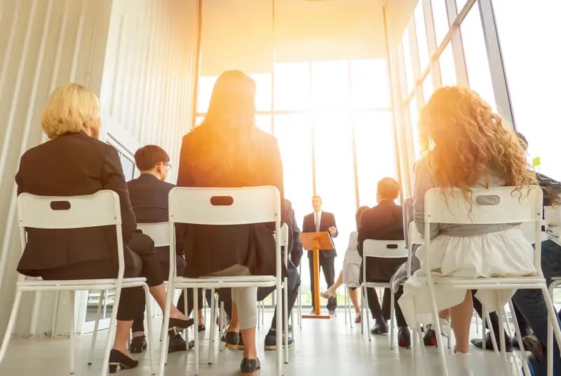 Workers sitting listening to a speaker in a meeting