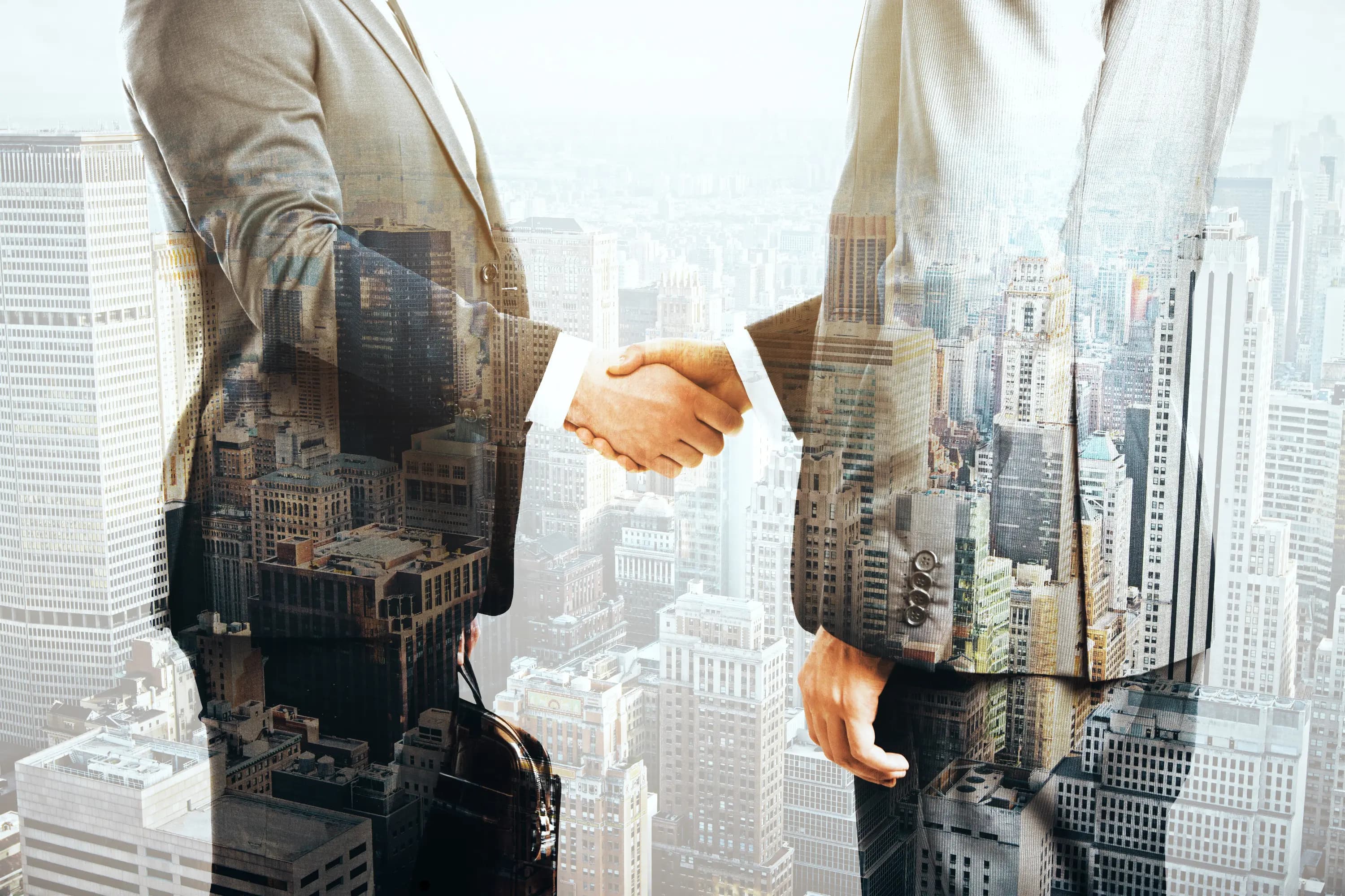 Double exposure of professionals shaking hands and buildings.